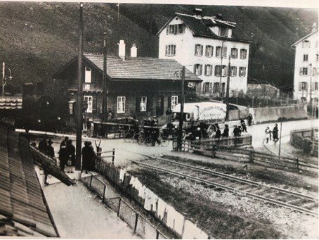 FussgängerInnen, Velos und ein Lastwagen warten an der Barriere neben dem Wärterhäuschen, bis die aus dem Zimmereggtunnel brausende Dampflok ihres Weges gezogen ist. Bild vor 1929. Quelle: SALU N1.05.45